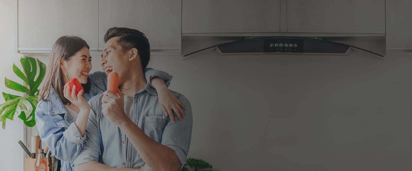 A happy young couple enjoying cooking and playing with vegetables in a well-designed kitchen.
