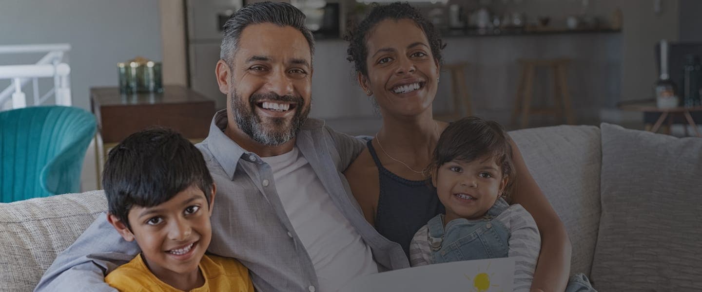 Proud happy parents of two kids relaxing on the couch in an open-concept living area.